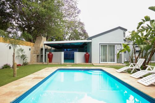 a swimming pool with two lawn chairs and a house at El-Gibor Best Guest House in Cape Town