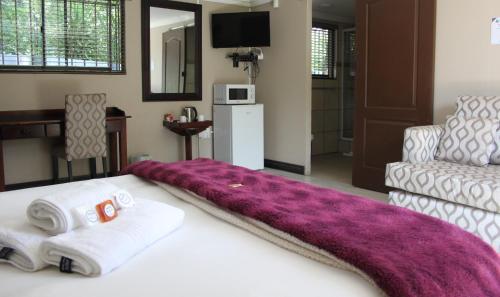 a bedroom with a bed with a purple blanket on it at Heimat Guesthouse in Welkom
