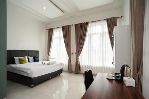 Tanjungkarang的住宿－Urbanview Hotel Bong Gajah Lampung，卧室配有一张床、一张书桌和窗户。