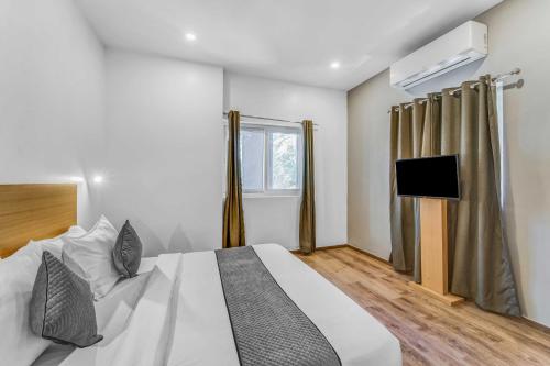 a bedroom with a white bed and a television at Rohaan Inn - UPAR Hotels Ashok Nagar in Chennai