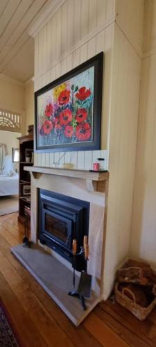 a fireplace in a living room with a painting on the wall at Amiens Cottage, historic, quiet, in heart of Stanthorpe in Stanthorpe
