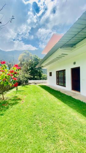 a house with a grass yard next to a building at Mountain Mansion Kodai in Kodaikānāl
