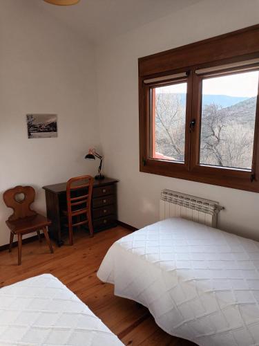 a bedroom with two beds and a desk and a window at Casa Rural Las Canales in Zapardiel de la Ribera