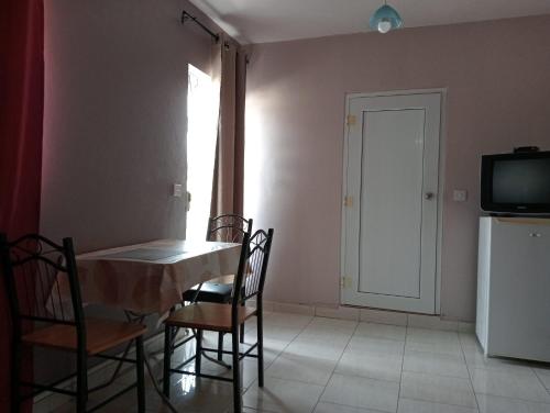 a dining room with a table and chairs and a television at Chetty Tourist Residence in Pereybere