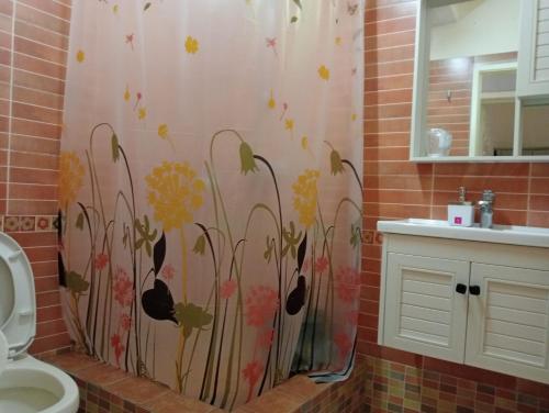 a bathroom with a shower curtain with flowers painted on it at Chetty Tourist Residence in Pereybere