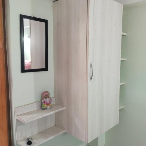 baño con espejo y armario con estanterías en Deep Home stay, en Agartala