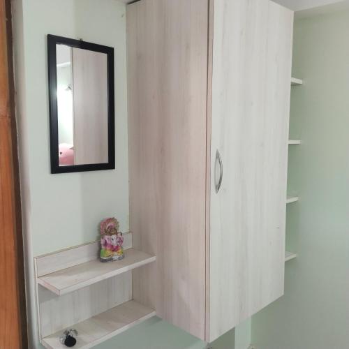 a bathroom with a mirror and a cabinet with shelves at Deep Home stay in Agartala
