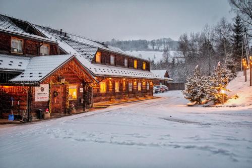 a log cabin in the snow with lights on at Czarna Owca in Istebna
