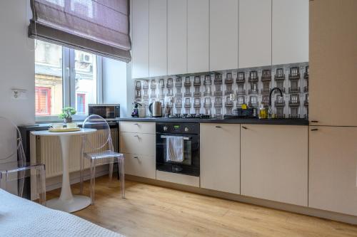 a kitchen with white cabinets and a stove top oven at Rent-Apart City Center Piotrkowska in Łódź