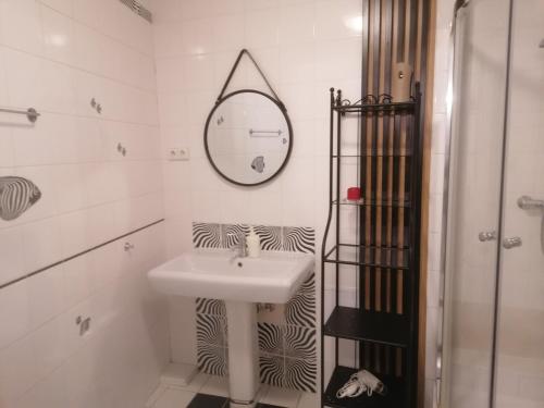 ein weißes Badezimmer mit einem Waschbecken und einem Spiegel in der Unterkunft Apartament Szczytna NO'10 in Toruń