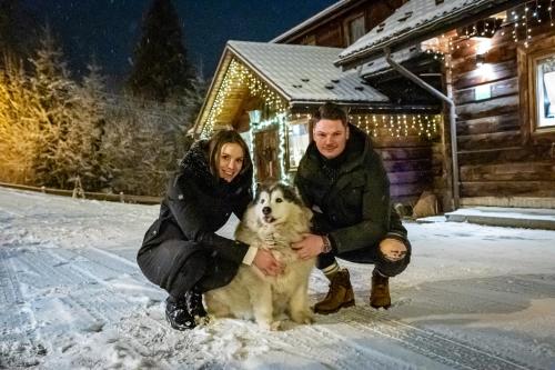 a man and a woman and a dog in the snow at Czarna Owca in Istebna