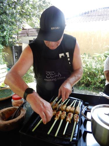 a man is cooking sausages on a grill at Villa Coco Bali in Seminyak