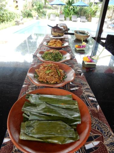 a long table with plates of food on it at Villa Coco Bali in Seminyak