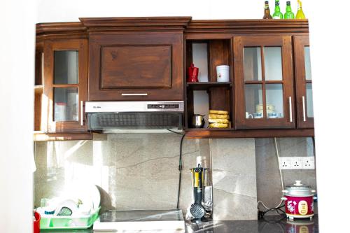 a kitchen with wooden cabinets and a microwave at Shan Star Weligama in Weligama