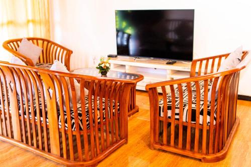 a living room with three chairs and a table and a television at Shan Star Weligama in Weligama