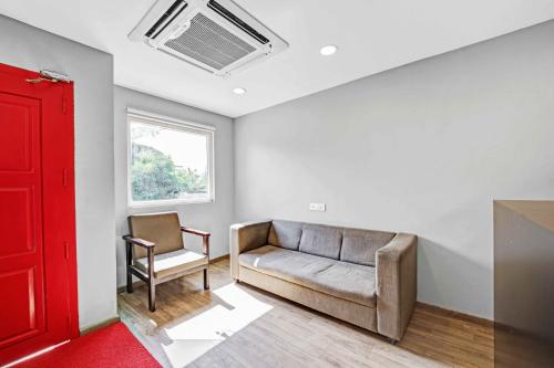 a living room with a couch and a red door at UPAR Hotels Uthandi, ECR in Chennai