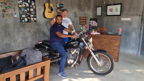 dos hombres están sentados en una motocicleta en una tienda en Sapphire Garden Hotel, en Habarana