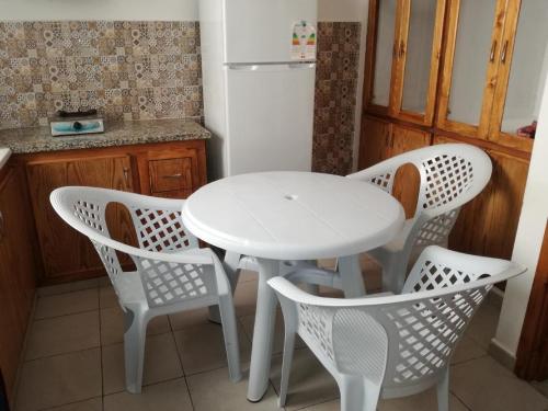 une table blanche et quatre chaises dans une cuisine dans l'établissement s 2 1 km from the beach mansoura kelibia, à Kelibia