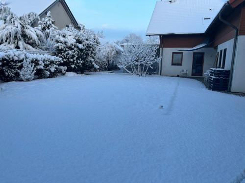a driveway covered in snow next to a house at Pension Zum Paradies in Harthausen