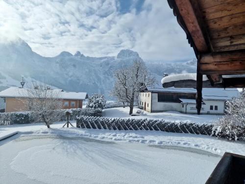 a snow covered yard with a house and mountains at Sonnleit'n Zimmer 6 in Abtenau