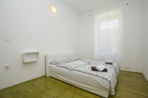 a white bedroom with a bed and a window at Apartment with garden and free parking in Pula