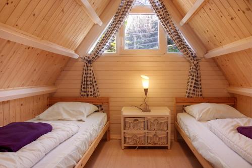 two beds in a wooden room with two windows at Casa Maro in Brezzo