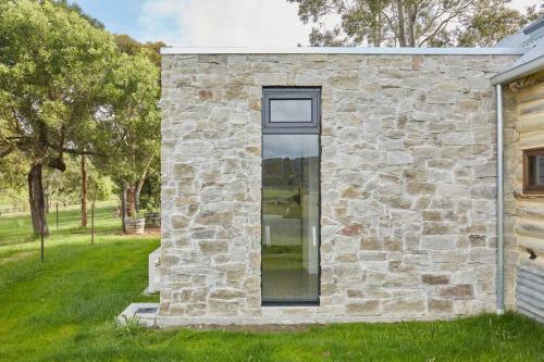 uma casa de pedra com uma janela ao lado em Luxury Yarra Valley Vineyard Log Cabin em Yellingbo
