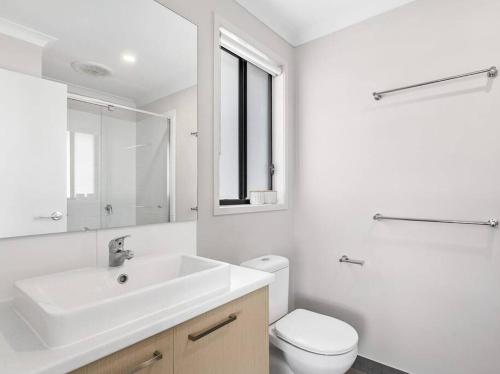 uma casa de banho branca com um lavatório e um WC em 28 BOWLING AVE POINT COOK em Point Cook