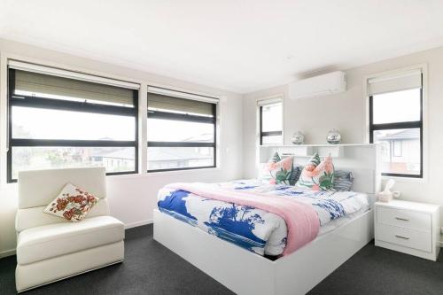 um quarto branco com uma cama e uma cadeira em 28 BOWLING AVE POINT COOK em Point Cook