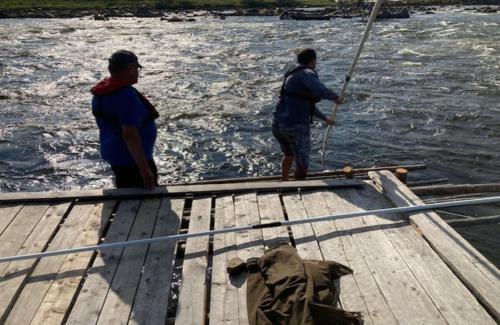 two men are standing on a boat in the water at Alanko Lodge in Tornio