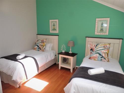 two beds in a room with blue and green walls at No 1 @ The Dunes in Plettenberg Bay