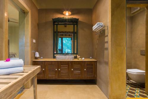 a bathroom with a sink and a toilet and a mirror at Vannraj Resort And Spa in Khawāsa