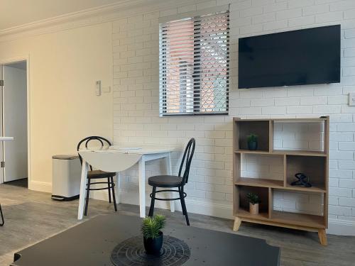 sala de estar con mesa y TV en la pared en Estelle Kramer Motel, en Armidale