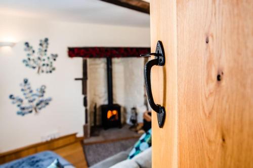 a door with a handle in a living room with a fireplace at Thursdays Corner Tudor Cottage in Church Stretton
