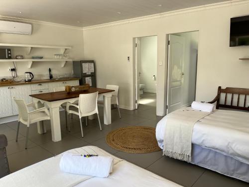 a room with two beds and a table and a kitchen at VIilla Vredenrust Guesthouse in Bloemfontein
