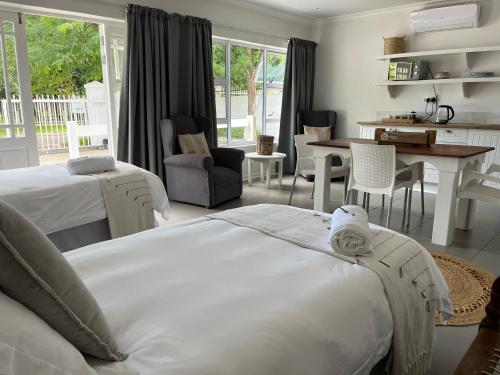 a bedroom with two beds and a kitchen and a table at VIilla Vredenrust Guesthouse in Bloemfontein
