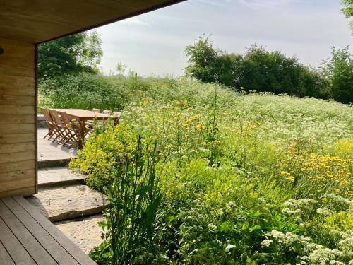 a wooden porch with a table and a field of flowers at Nachtegael Zomerhuis, idyllische woning in de Vlaamse Ardennen in Kluisbergen