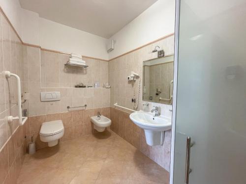 a bathroom with a sink and a toilet and a mirror at Hotel Oasi Beach in Malcesine