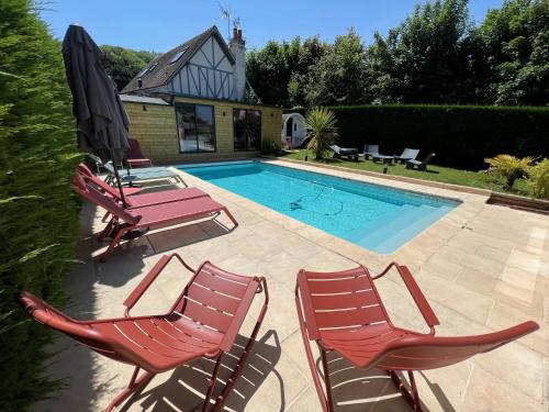- une piscine avec 2 chaises et un parasol dans l'établissement Villa l'Hermitage Piscine Sauna Fitness Deauville, à Benerville-sur-Mer