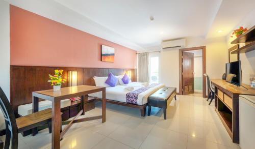 a bedroom with a bed and a desk and a television at Ratana Hotel Sakdidet, PHUKET TOWN in Phuket