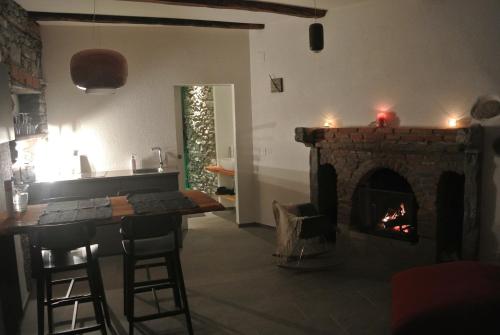 a living room with a fireplace and a table and a kitchen at A Cà balade in Design in Miglieglia