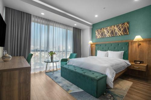 ein Hotelzimmer mit einem Bett, einem Schreibtisch und einem Fenster in der Unterkunft Royal Tulip Hotel & Casino, Tbilisi in Tbilisi City