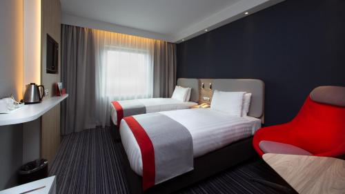 una camera d'albergo con due letti e una sedia rossa di Holiday Inn Express Geneva Airport, an IHG Hotel a Ginevra