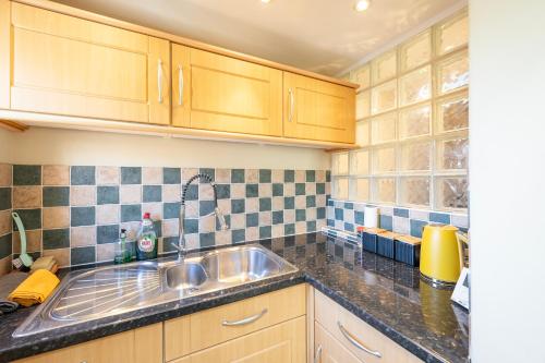 una cocina con armarios de madera y fregadero en Fabulous 2 bedroom cottage in fantastic Clifton - Simply Check In, en Bristol