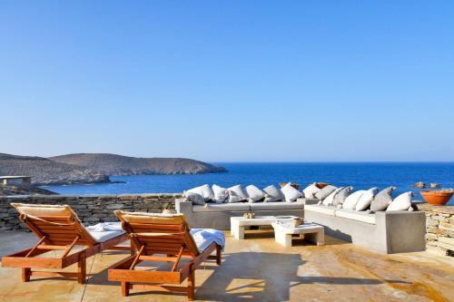 a living room with a couch and chairs and the ocean at The Charming Waterfront Retreat, with a swimming pool & direct access to the sea, ideal for large families, or a group of friends in Otzias