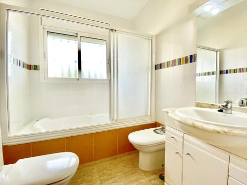 een badkamer met een wastafel, een toilet en een raam bij Villa Mila in L'Ametlla de Mar