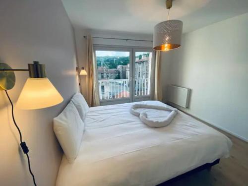 un letto bianco in una stanza con finestra di T3 Hypercentre-dernier étage-Balcon-Garage-Queen beds-vue panoramique a Saint-Étienne
