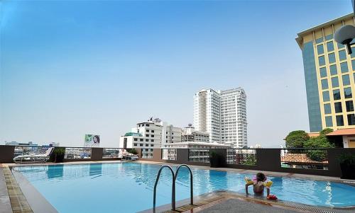 un bambino che gioca in una piscina in cima a un edificio di Royal Lanna Hotel a Chiang Mai