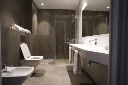 a bathroom with two sinks and a toilet and a shower at Hotel Bodega FyA - GRUPO PIÉROLA in Navarrete