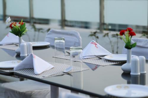 a glass table with plates and napkins on it at Hotel Atithi, Aurangabad in Aurangabad